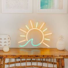 a wooden table topped with a neon light next to two pictures on the wall behind it