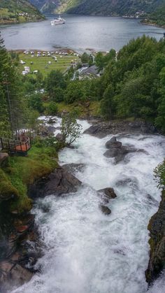 a river flowing through a lush green forest covered hillside next to a small town on the side of a mountain