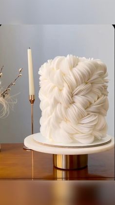 a white cake sitting on top of a table next to a candle