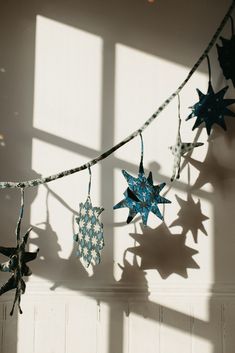 some paper stars are hanging from a string in the sun with long shadows on the wall