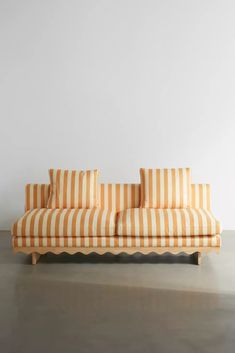 an orange and white striped couch sitting on top of a cement floor next to a wall