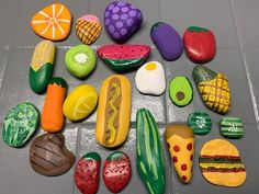 many different types of painted rocks are arranged on the floor, including one with a hot dog