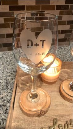 a wine glass sitting on top of a wooden tray next to a lit candle holder