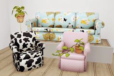 two chairs and a couch in a room with wooden floors, one has a cow pattern on it