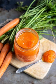 some carrots are sitting on a cutting board next to a jar of jam