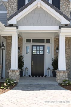 the front entrance to a house with two potted plants on either side and an entry door