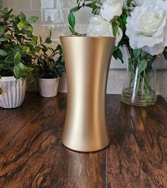 two vases with white flowers in them on a table