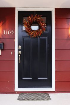 a black front door with a wreath and two lights on the side of it that says 1035