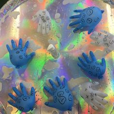 several blue hand puppets are on top of a holographic plate with rainbow colors