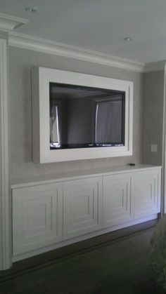 a flat screen tv mounted to the side of a wall in an empty living room