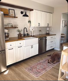 a dog laying on the floor in a kitchen next to an oven and dishwasher