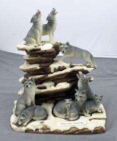 a group of wolf figurines sitting on top of a pile of snow covered rocks