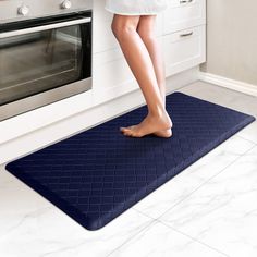 a woman standing on a kitchen mat in front of an oven with her feet up