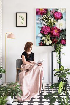 a woman sitting in a chair with a blanket on her lap looking at a magazine