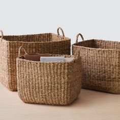 three woven baskets with handles on top of a table next to a card holder and envelope