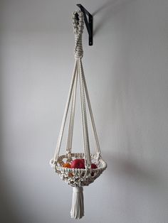 a macrame hanging basket with apples in it