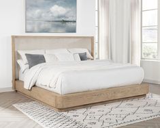 a large bed sitting on top of a wooden floor next to a white and gray rug