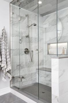 a bathroom with white marble walls and flooring, shower stall and standup shower