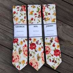 three ties with floral designs on them sitting on a wooden surface