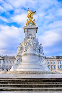 a large white monument with gold statues on it's sides and steps leading up to the building