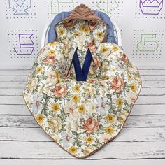 an infant car seat cover with flowers on it and a blue ribbon hanging from the back