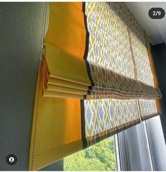 an orange and yellow roman blind in front of a window with the blinds pulled back