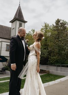 a bride and groom standing in front of a church