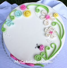 a white cake decorated with flowers and a lady bug