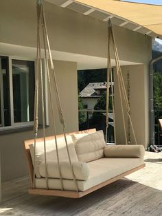 a white couch sitting on top of a wooden floor next to a patio swing chair