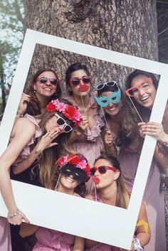 a group of women wearing masks pose for a photo in front of a tree