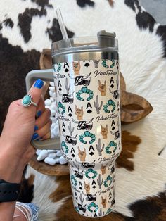 a woman is holding a travel mug in front of a cow print rug with the words alpacas on it