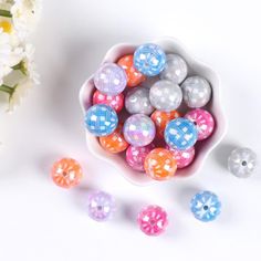 small plastic balls in a bowl next to flowers