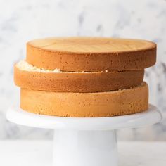 three layers of cake sitting on top of a white cake platter with marble background