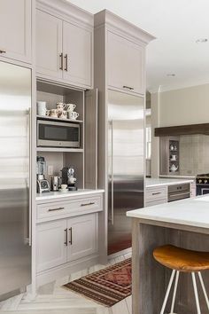 a large kitchen with stainless steel appliances and white counter tops, along with an area rug on the floor