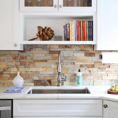 a kitchen with white cabinets and marble backsplashing, bookshelf above the sink