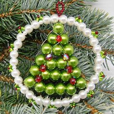 a christmas tree ornament hanging from a pine tree with pearls and beads on it