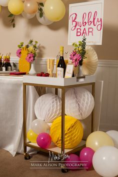 a table topped with balloons and bottles of wine next to a sign that says bubbly bar