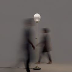 blurry image of two people walking past a lamp