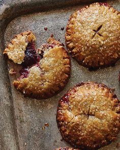 four pies sitting on top of a baking pan covered in crumbled crust