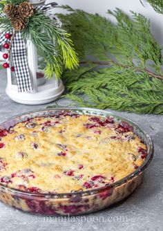 a casserole dish with cranberry sauce and pine branches in the background