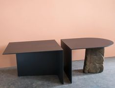 two black tables sitting next to each other in front of a pink wall and floor