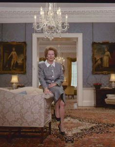 a woman sitting on top of a couch next to a chandelier