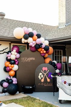 an outdoor party with balloons and decorations on the front lawn, including a sign that says it's halloween