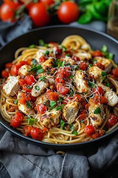 a plate of pasta with chicken, tomatoes and parmesan cheese