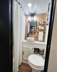 a white toilet sitting under a bathroom mirror next to a sink and shower stall in a bathroom