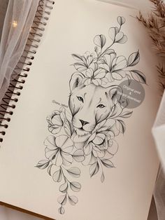 a drawing of a lion surrounded by flowers on a spiral notebook next to some feathers