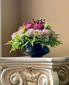 a blue vase filled with purple flowers on top of a white table next to a mirror