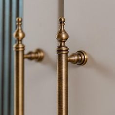 two golden metal poles are next to each other in front of a white wall and mirror