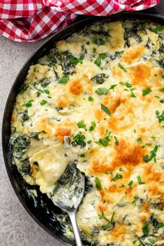 a casserole with spinach and cheese in a black skillet on a table