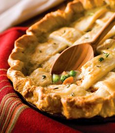 a close up of a pie on a red cloth with a wooden spoon in it